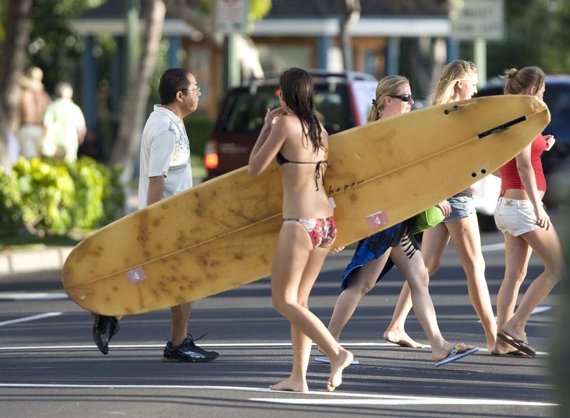 Turista a spasso per le strade di Waikiki con la tavola sottobraccio. (Reuters)